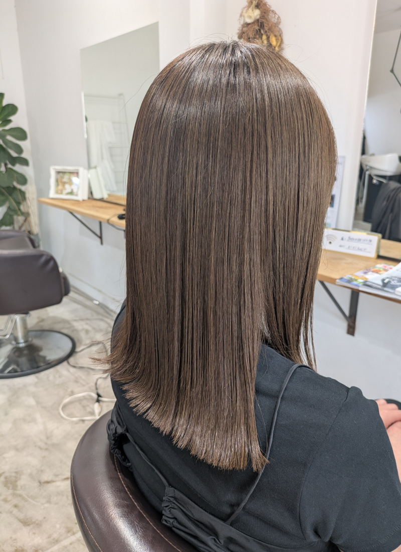 サロン内でのツヤのある黒髪のロングストレートヘア（後ろ姿）