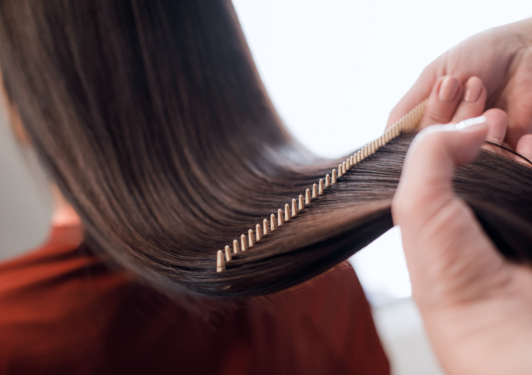 美容師が美しいストレートヘアをコームでとかしている様子